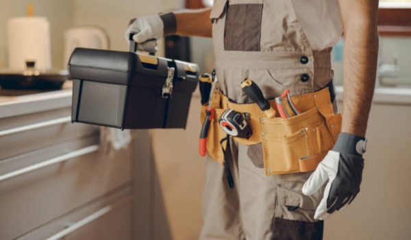 Close up of professional handyman standing on home kitchen and holding his tool bag